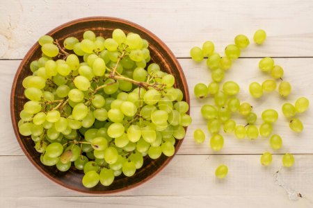 Photo for Sweet organic grapes with clay plate on wooden table, macro, top view. - Royalty Free Image