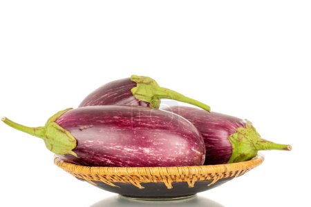 Photo for Three organic ripe eggplants on a ceramic plate, macro, isolated on white background. - Royalty Free Image