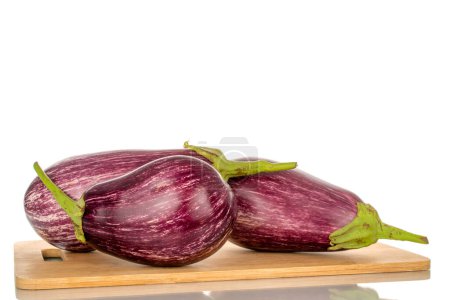 Photo for Three organic ripe eggplants on a wooden kitchen board, macro, isolated on white background. - Royalty Free Image