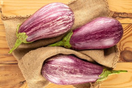 Photo for Two ripe eggplants with a jute bag on a wooden table, macro, top view. - Royalty Free Image