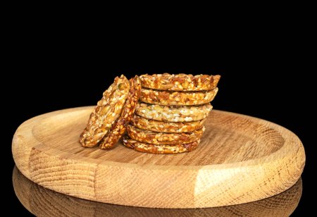 Plusieurs biscuits Thaler sucrés sur une assiette en bois, macro, isolés sur fond noir.