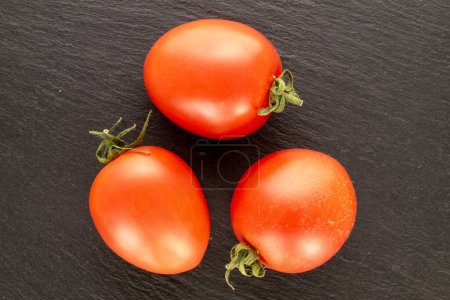 Foto de Tres tomates cóctel en piedra pizarra, macro, vista superior. - Imagen libre de derechos