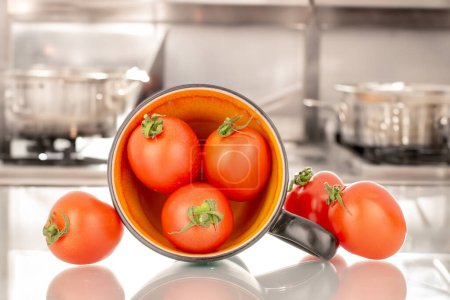 Foto de Varios tomates de cóctel maduros con taza de cerámica, macro, en el fondo de la cocina - Imagen libre de derechos
