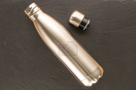 Photo for One metal thermos bottle on slate stone, macro, top view. - Royalty Free Image