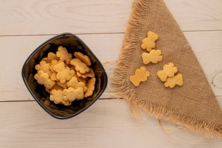 Délicieux biscuits en forme d'ours dans une assiette en céramique sur une table en bois, vue sur le dessus, macro.