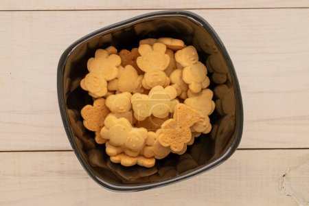 Delicious cookies in the shape of a bear in a ceramic plate on a wooden table, top view, macro.