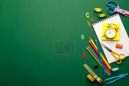 Retour à l'école. Fournitures scolaires stationnaires colorées sur fond vert, espace ou texte plat