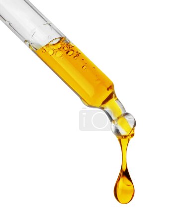 Gotas de un líquido aceitoso amarillo que gotea de una pipeta aislada sobre un fondo blanco