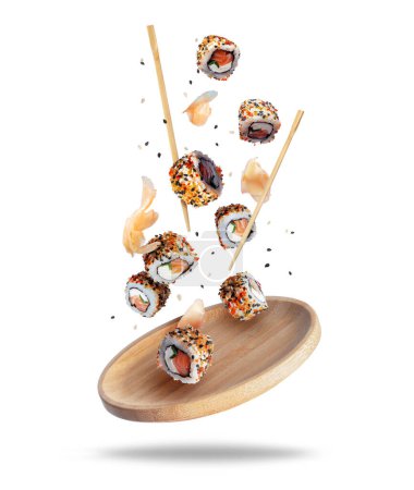 Świeże bułki sushi z imbirem spadające na drewnianą płytę izolowaną na białym tle