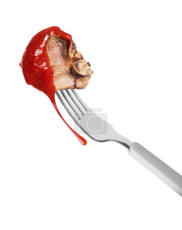 Fried beef steak poured with tomato ketchup on a fork close up on a white background