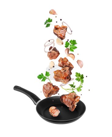 Grilled beef steaks with garlic and parsley fall on a frying pan on a white background