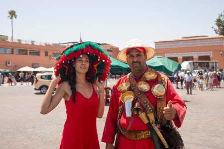 Photo for Marrakech, Morocco - November 8, 2022: Sexy tourist with a big hat a seller of water from Marrakech, this type of commercials are very common, traditional and tourist attraction of this Arab city. - Royalty Free Image