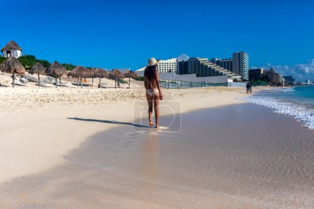 Foto de Sexy turista caminando por la playa de delfines hacia la zona hotelera de Cancún México disfrutando del mar Caribe turquesa. Esta es una playa tropical paradisíaca de arena blanca y dorada del Caribe. - Imagen libre de derechos