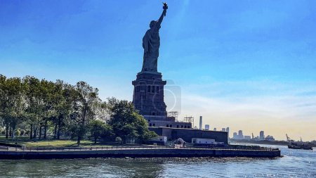 Foto de La dama de Nueva York (EEUU) vista desde atrás y un barco, es como se conoce, se visita y se conoce la estatua de la libertad de la Gran Manzana en todo el mundo. - Imagen libre de derechos