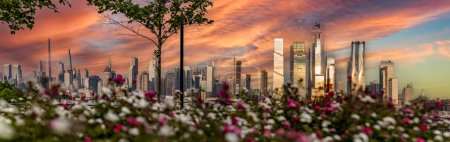 Téléchargez les photos : New York, États-Unis, 3 juin 2023 : Vue panoramique avec des fleurs et le magnifique coucher de soleil orange avec les gratte-ciel de Manhattan. - en image libre de droit