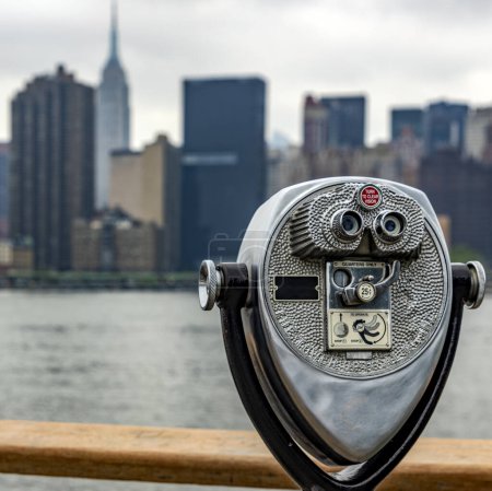 Foto de Un binocular en Long Island que es una isla que se extiende a través de Nueva York (EE.UU.) y desde donde se puede ver perfectamente el horizonte de Manhattan con los rascacielos de la Gran Manzana. - Imagen libre de derechos
