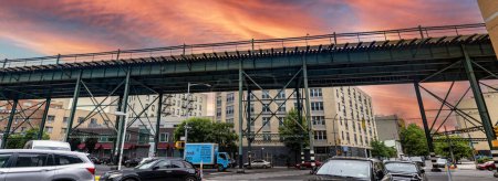 Photo for New York, USA; June 3, 2023: Typical overhead train and streetcar tracks of the Bronx, a neighborhood in the Big Apple, under an orange sky at sunset. - Royalty Free Image