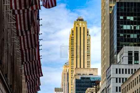 Photo for American flags flying on the typical and popular buildings of Manhattan, in the heart of the Big Apple in New York City (USA). - Royalty Free Image