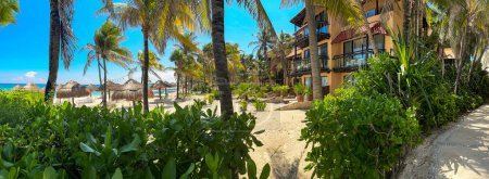Panoramablick auf einen paradiesischen weißen Sandstrand mit dem Hintergrund des karibischen Meeres, unter warmer Sonne und grüner karibischer Vegetation.