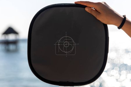 Una tarjeta gris que mide la luz de una playa caribeña, para obtener una fotografía correctamente expuesta conociendo la medición de la luz.