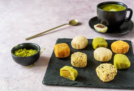 A sophisticated spread of mochi in various textures and a bowl of matcha powder, ready for a traditional Japanese tea time experience.