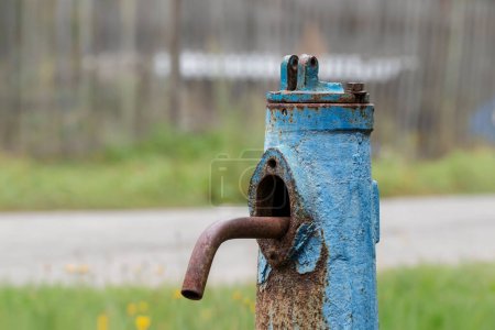 Photo for An old water column with blue cracked paint in the village. Close-up of a drinking water supply column. - Royalty Free Image