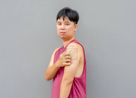 Téléchargez les photos : Asiatique homme gratter démangeaisons avec la main sur le haut du bras, concept de soins de santé - en image libre de droit