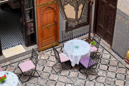 Foto de Mesa redonda con cuatro sillas a su alrededor en el patio de un riad tradicional en Fez - Imagen libre de derechos