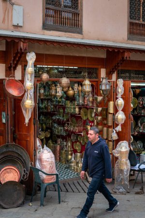 Téléchargez les photos : Homme marchant près d'un bazar de cuivre dans la vieille médina de Fès - en image libre de droit