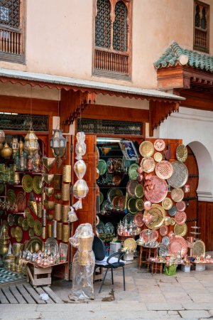 Téléchargez les photos : Produits en cuivre faits à la main devant un bazar dans l'ancienne médina de Fès - en image libre de droit