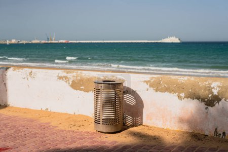 Photo for Metal railing trash bin on the promenade nearby a Mediterranean beach - Royalty Free Image