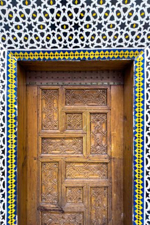 Photo for Wooden door surrounded with mosaic wall decorated in Moroccan tiles at Zawiya of Moulay Idris II in Fez, Morocco - Royalty Free Image