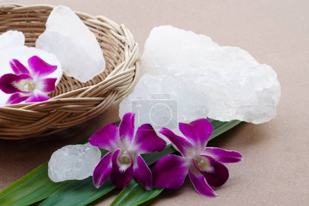Photo for Crystal clear alum stones or Potassium alum decorated with flowers and leaves.  Useful for beauty and spa treatment. Use to treat body odor under the armpits as deodorant and make water clear. - Royalty Free Image