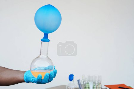 Téléchargez les photos : Science experiment , Hand holds transparent bottle with inflated blue balloon on top of bottle. The experiment about air or gas reaction.by using chemical substance. Concept,  Science Education - en image libre de droit