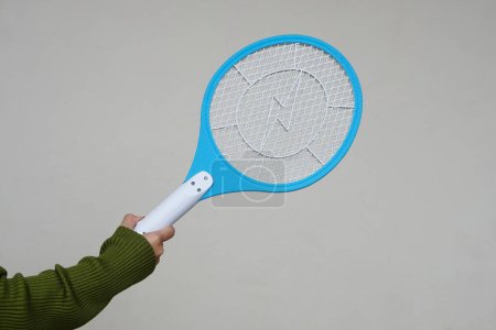 La mano de primer plano sostiene la raqueta eléctrica del swatter del mosquito. Concepto, dispositivo eléctrico para matar mosquitos, insectos, insectos por swatting a insectos voladores.       