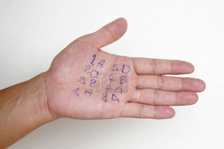 Foto de De cerca la mano con números escritos y letras. Estudiante escribir respuesta en la palma. Concepto: engañar a la prueba. Comportamiento deshonesto. Evaluación de la educación. - Imagen libre de derechos
