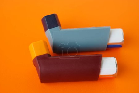 Téléchargez les photos : Inhalateurs d'asthme sur fond orange. Concept, produits pharmaceutiques pour le traitement des symptômes de l'asthme ou de la BPCO. Utilisation sur ordonnance. Appareil de soins de santé à domicile. - en image libre de droit
