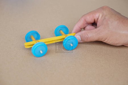 Hand hold handmade toy racing car made from ice cream sticks and bottle caps. Concept, Recycling kids toy. Easy to do, creative DIY craft that kids can do. Fun lesson              