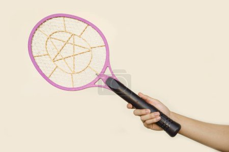 Closeup hand holds mosquito electric swatter racket. Concept, electric device to kill mosquitoes, insects, bugs by swatting to flying insects.         