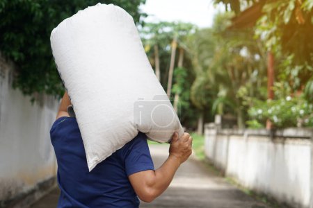 Photo for Back view of strong man holding heavy sack on his shoulders. Concept, hard- working, laborer. Working against poverty. Man carry sack to delivery. Service to home. Lifestyle - Royalty Free Image