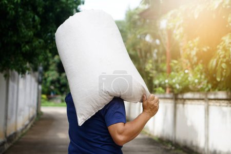Photo for Back view of strong man holding heavy sack of rice grains on his shoulders. Concept, hard- working , laborer . Working against poverty. Man carry sack to delivery. Service. - Royalty Free Image