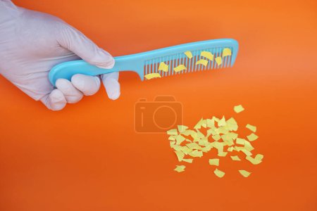 Photo for Comb and small pieces of paper. Equipment, prepared to do experiment about static electricity. Orange background. Concept, Science lesson, fun and easy experiment. Education. Teaching aids. - Royalty Free Image