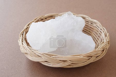 Crystal clear alum stones or Potassium alum on basket isolated on brown background. Useful for beauty and spa treatment. Use to treat body odor under the armpits as deodorant and make water clear.