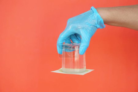 Nahaufnahme Hand halten und drehen Sie ein Glas Wasser nach unten. Das Glas mit Papier bedecken. Konzept, wissenschaftliches Experiment über Luft und Flüssigkeitsdruck.  