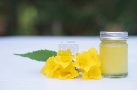 Eine Flasche hausgemachte thailändische Kräutersalbe, Balsam. Dekoriert mit gelben Blüten. Konzept, thailändische Weisheit zur Verwendung duftender Heilkräuter zur Herstellung von Inhalations- und Massagebalsam.            