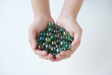 Close up hands holds marbles balls, small spherical object often made from glass, clay, steel, plastic, or agate. Concept. object use as toy for playing games or use for DIY craft decoration.   