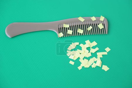 Comb and small pieces of paper. Equipment, prepared to do experiment about static electricity. Green background.  Concept, Science lesson, fun and easy experiment. Education. Teaching aids.           