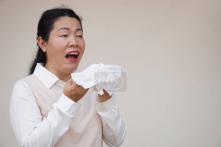 Téléchargez les photos : Femme asiatique éternue, bouche ouverte, tient du papier de soie blanc. Concept, problèmes de santé. Malade, malade et grippé. Couvrez la bouche lorsque vous toussez ou éternuez pour arrêter la propagation des germes, des maladies - en image libre de droit