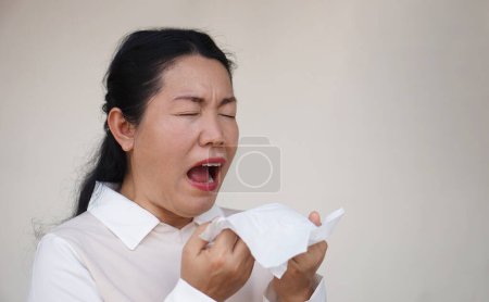 Téléchargez les photos : Femme asiatique éternue, bouche ouverte, tient du papier de soie blanc. Concept, problèmes de santé. Malade, malade et grippé. Couvrez la bouche lorsque vous toussez ou éternuez pour arrêter la propagation des germes, des maladies - en image libre de droit