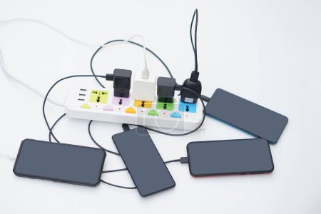 Photo for Mobile Phone connected to charging hubs on electric socket. Concept, too many devices plugged in can cause severe damage with appliance as electric shot. Overloaded electrical outlets. Dangerous. - Royalty Free Image